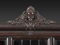 An Aesthetic Movement Crane and Mask Carved Mahogany and Glass Paneled Bookcase