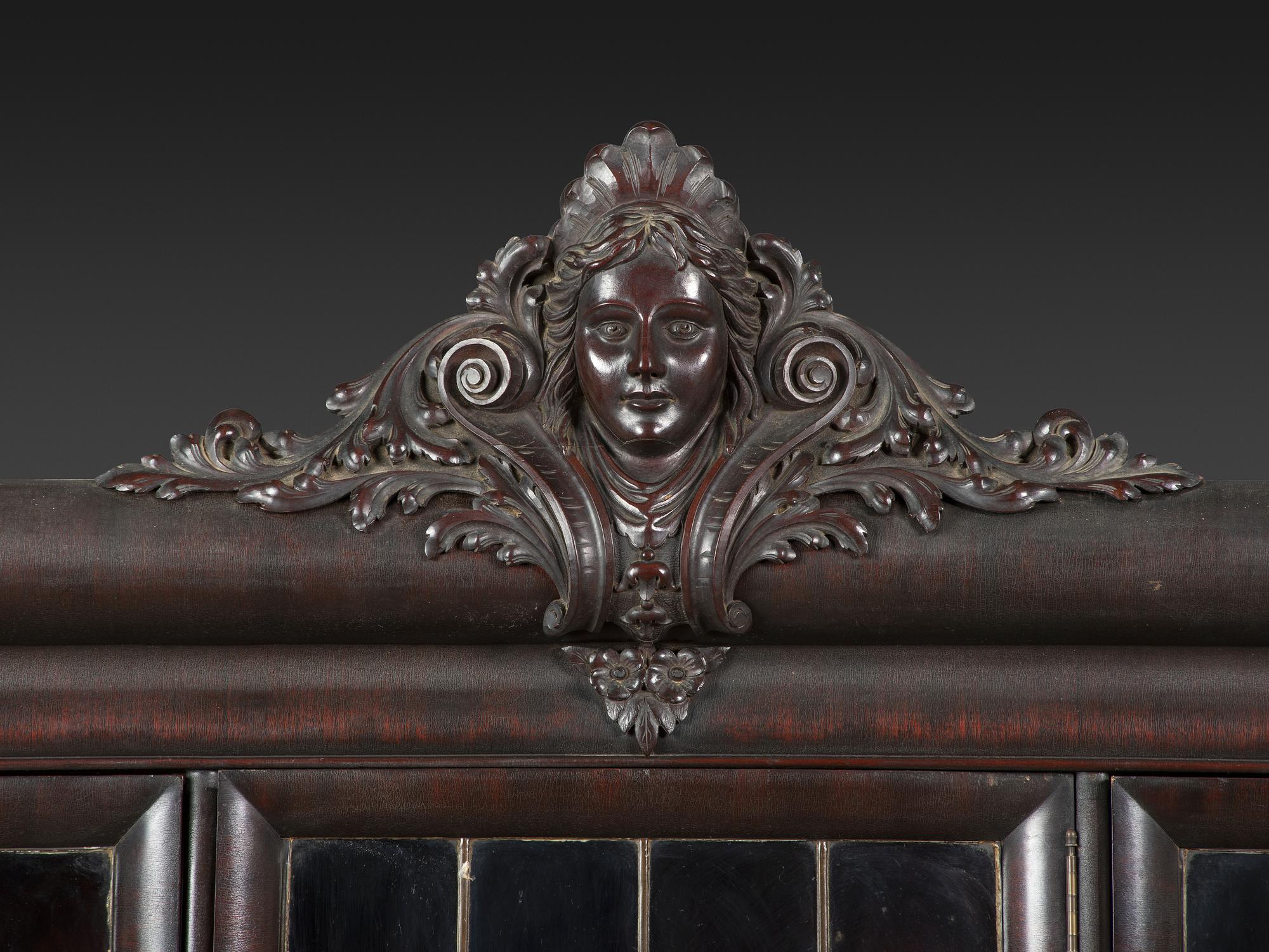 An Aesthetic Movement Crane and Mask Carved Mahogany and Glass Paneled Bookcase