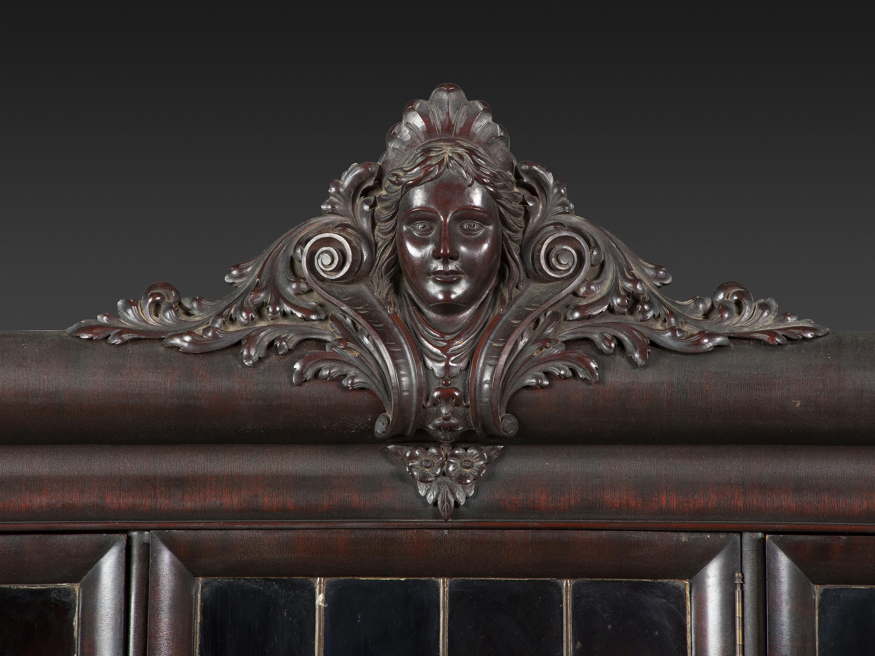An Aesthetic Movement Crane and Mask Carved Mahogany and Glass Paneled Bookcase