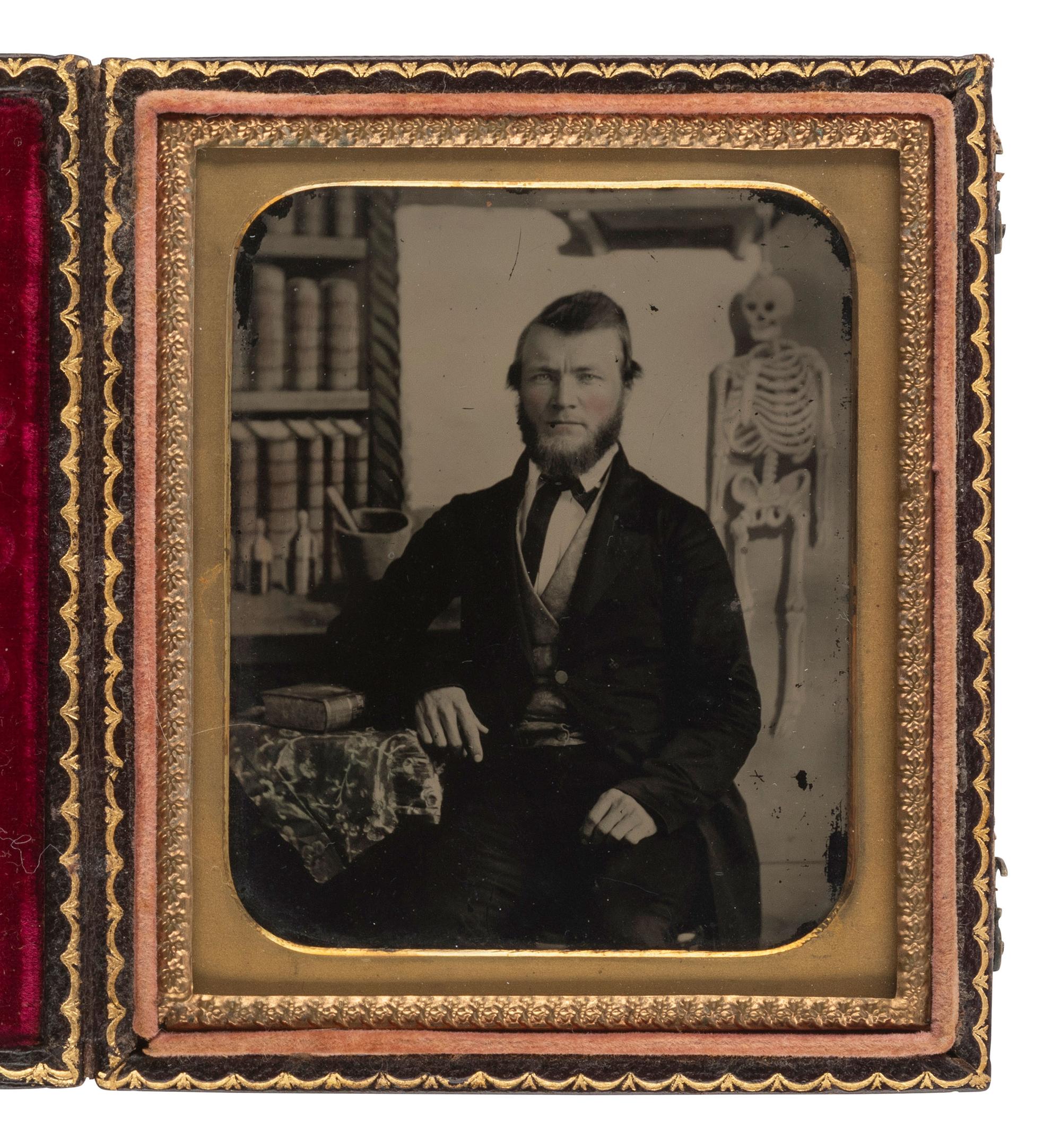 [EARLY PHOTOGRAPHY]. Sixth plate ambrotype of a young doctor with skeleton in painted background.