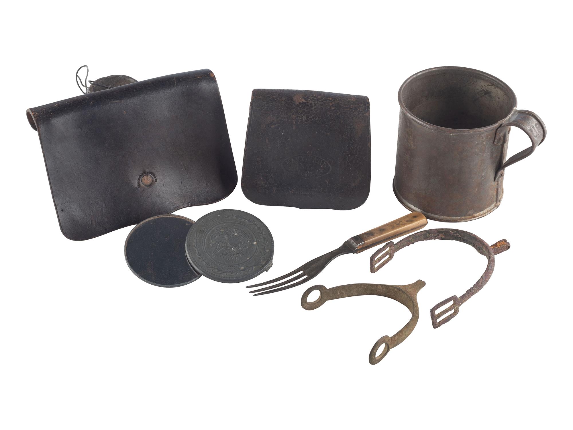 [CIVIL WAR]. A group of 7 items used by a soldier in the field, incl. US issued military cup, Navy fuse pouch, pistol cartridge box, bone handled fork, mirror with patriotic motif, and two dug spurs from the battlefield.