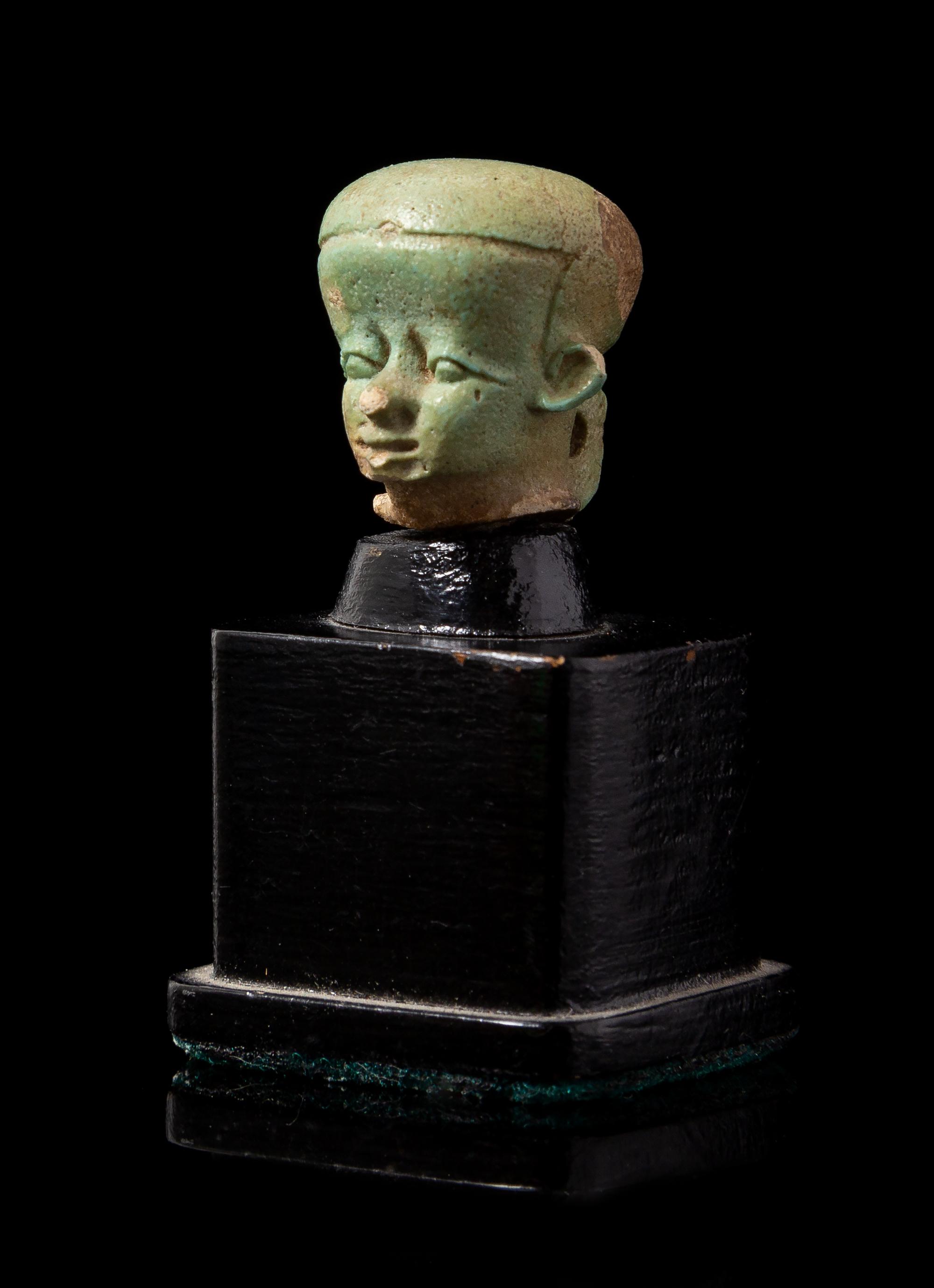 An Egyptian Faience Head of Pataikos Height 3/4 inches. — PTOLEMAIC PERIOD, 304-30 B.C.E.