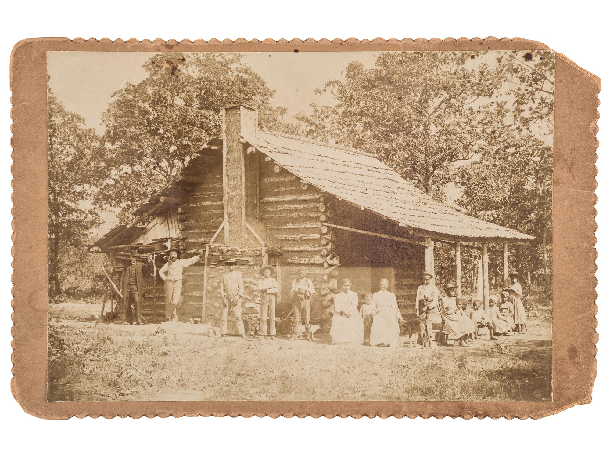 [EARLY PHOTOGRAPHY]. A group of 2 cabinet photographs of African American families posing in front of log cabins. Ca 1890s.