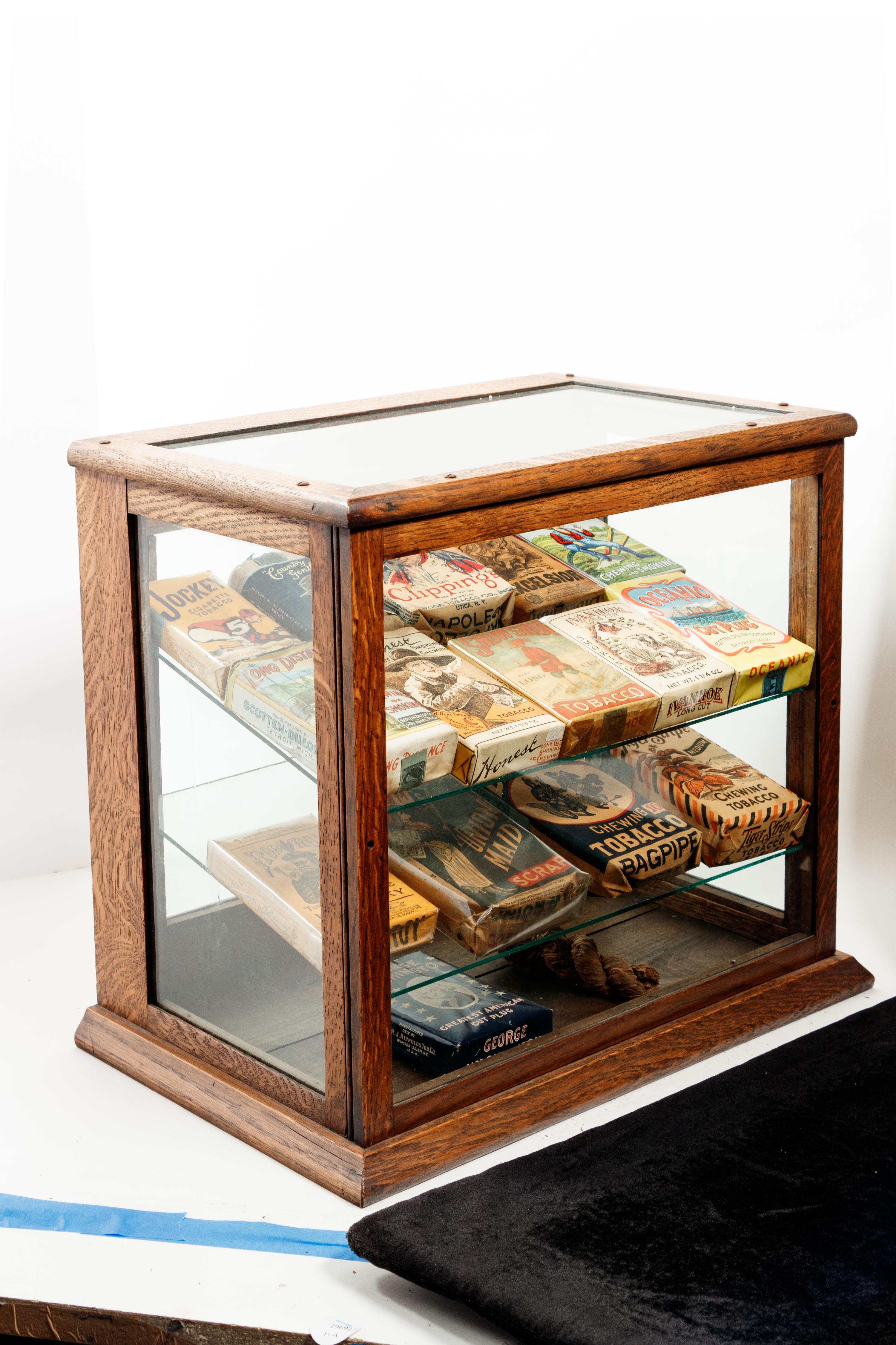 A Collection of Fifteen Tobacco Cartons and a Tobacco Rope in Display Case