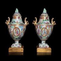 A Pair of Chinese Export Canton Famille Rose Porcelain Covered Urns, Early 19th Century — 清晚期 外銷廣彩人物故事圖獎杯形賞瓶一對