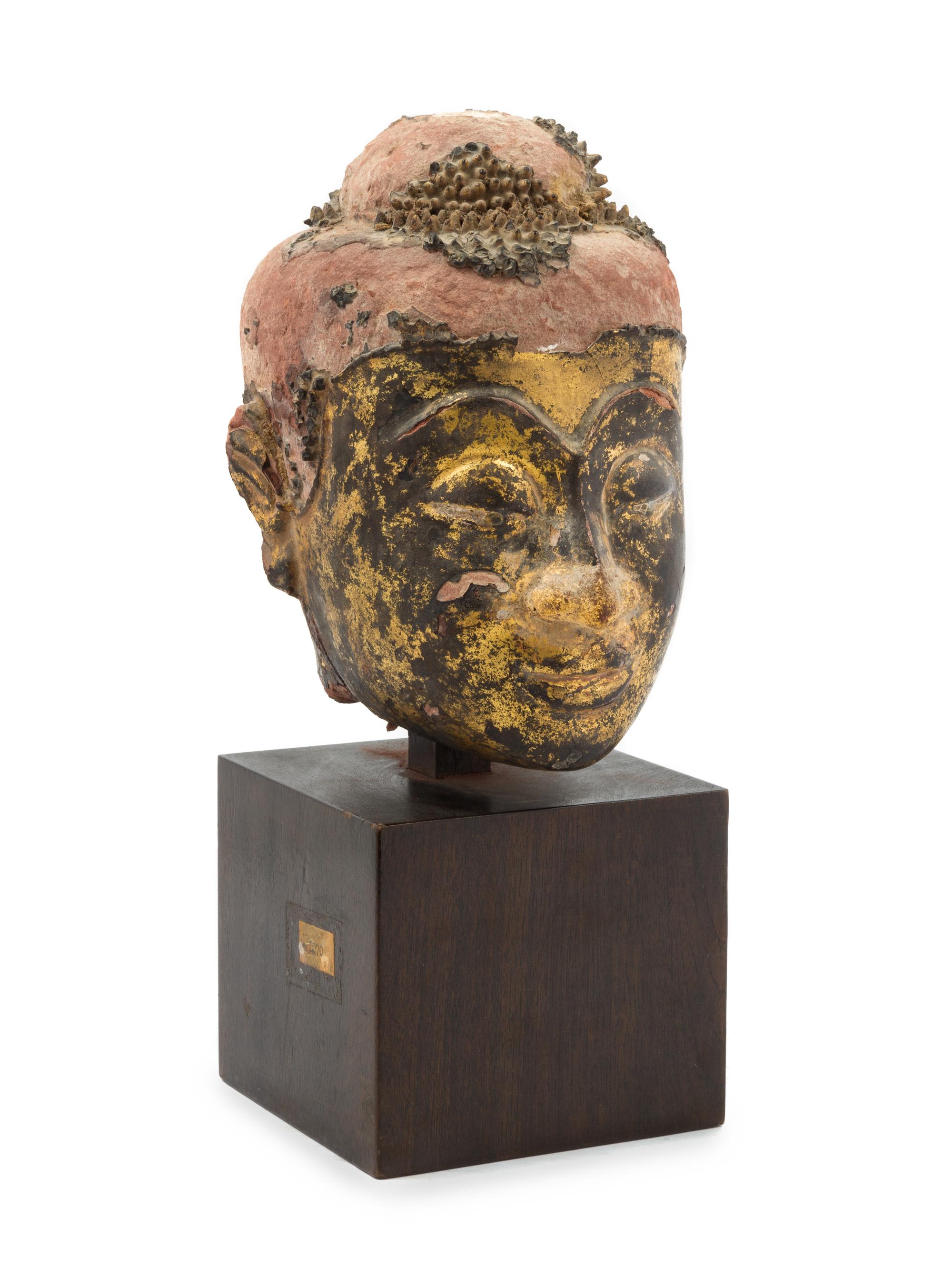 A Thai Parcel Gilt and Lacquered Terra Cotta Head of Buddha 16TH CENTURY OR EARLIER Height overall 12 3/8 inches. — 16TH CENTURY OR EARLIER