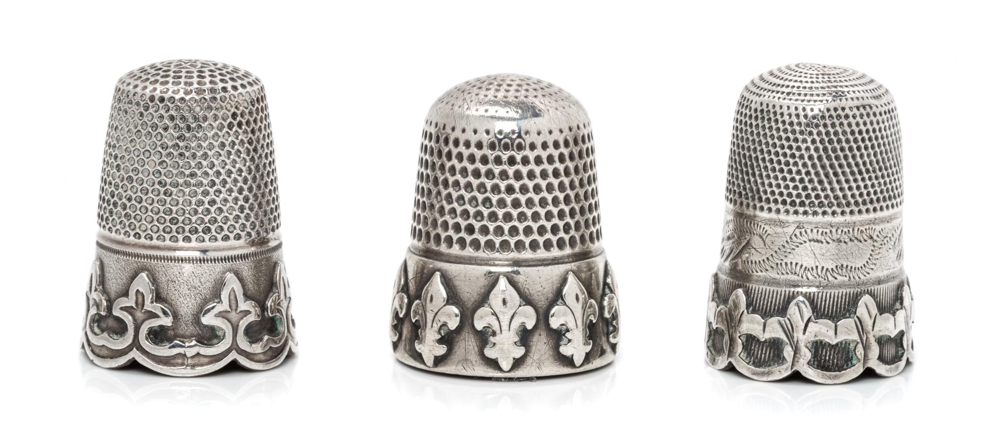 A Group of Three Silver Thimbles, Various Makers, each having a knurled top and body above a band worked to show fleurs-de-lis.