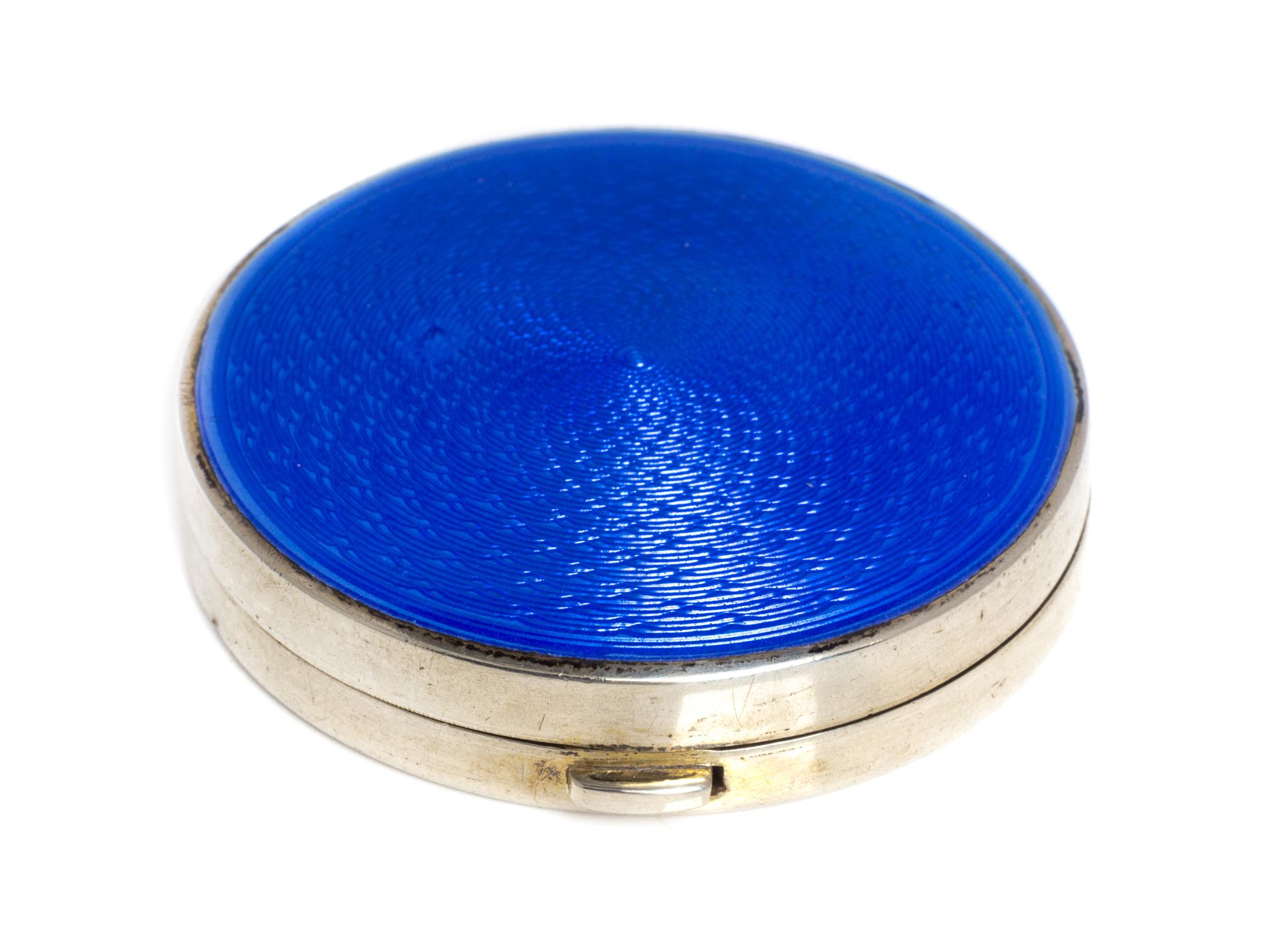 An Edwardian Silver and Enamel Box, Crisford & Norris, Birmingham, 1909, of circular form, the lid with blue guilloche enamel and openi