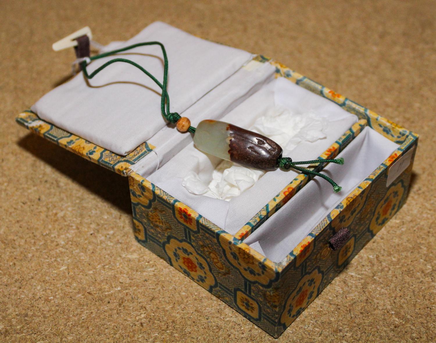 A Celadon and Russet Jade Bead. Length 1 1/2 inches.