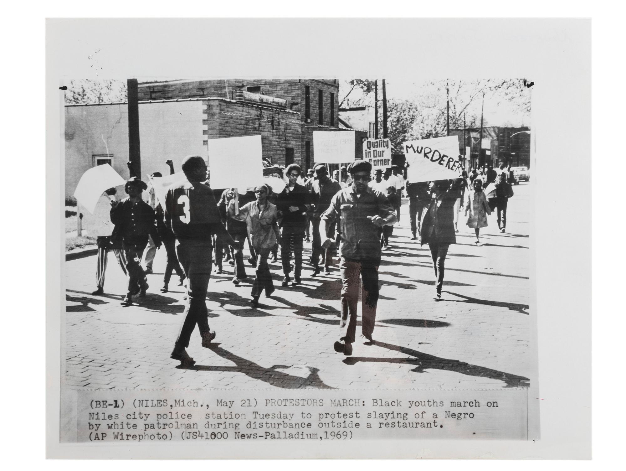 [CIVIL RIGHTS]. Press photograph of African American youths marching on the Niles, MI, police station to protest the slaying of an African American by a white patrolman during a disturbance. Niles, MI, 27 May 1969.