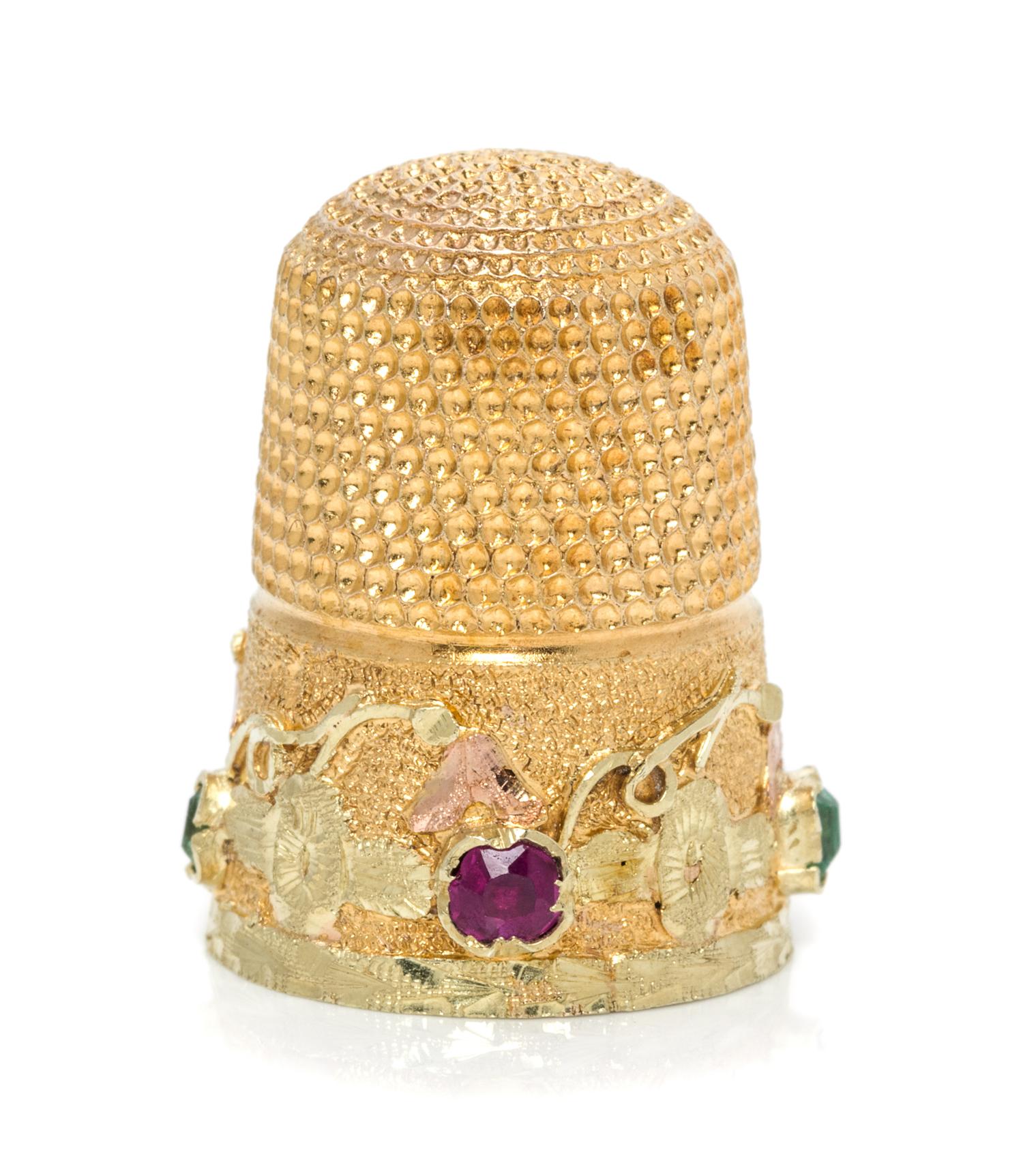An American Gold and Gemstone Thimble, , the knurled top and body above a floral and foliate band inset with two rubies and two green b