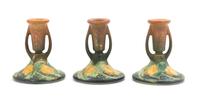 A Set of Three Roseville Sunflower Pottery Candlesticks Height of each 4 1/4 inches.
