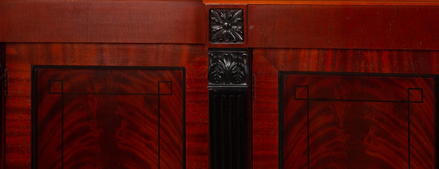 A Late Regency Style Figured Mahogany Sideboard with Carved Ebonized Pilasters