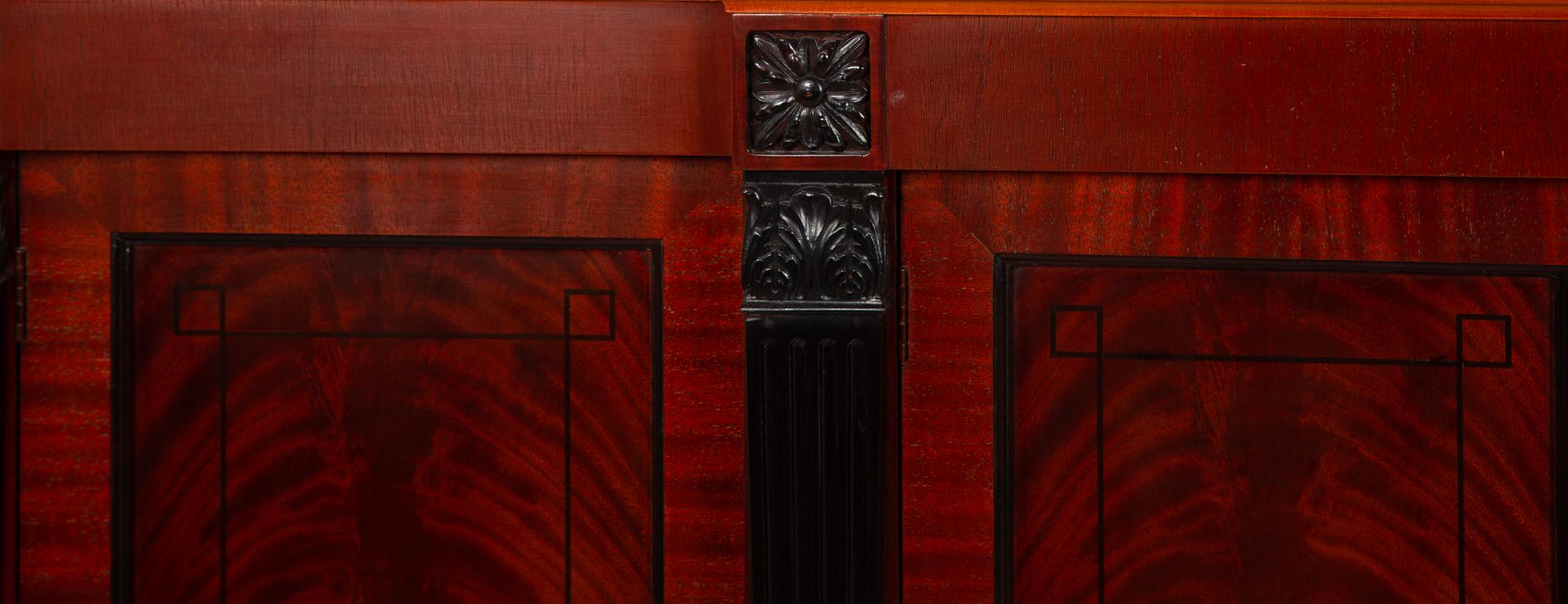A Late Regency Style Figured Mahogany Sideboard with Carved Ebonized Pilasters