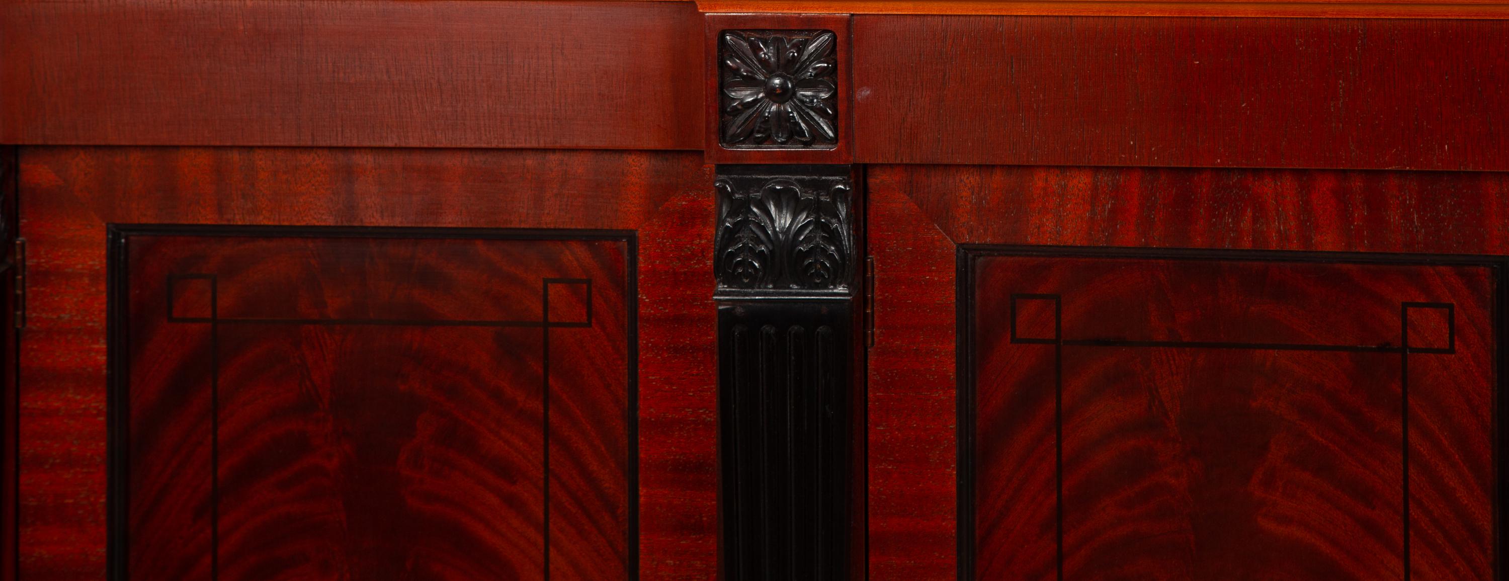 A Late Regency Style Figured Mahogany Sideboard with Carved Ebonized Pilasters