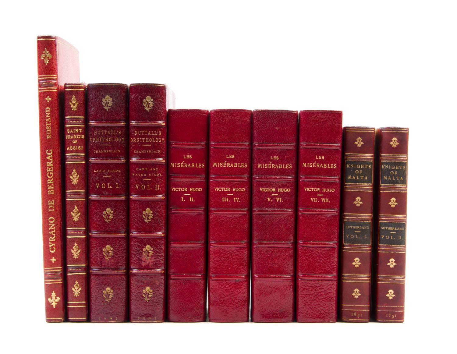 (BINDINGS) A group of 11 books bound in shades of red leather.