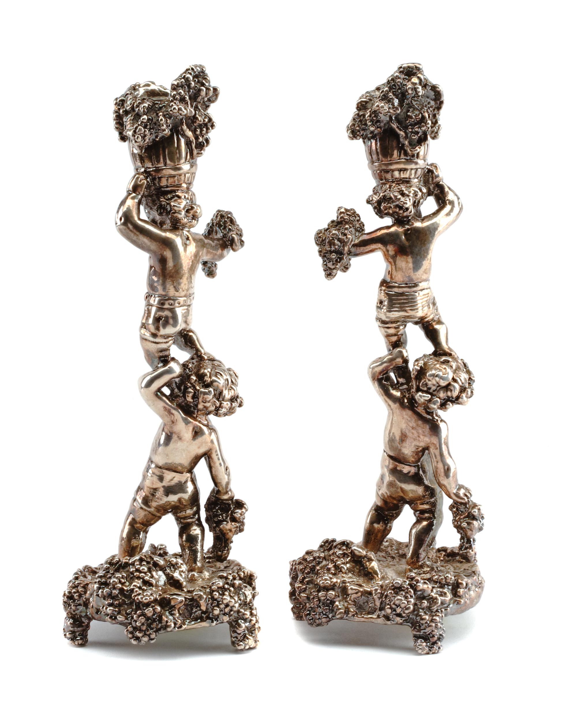 A Pair of Silver Figural Candlesticks, Circa 2000, each in the form of two Bacchanalian putti supporting a bushel of grape bunches, wei