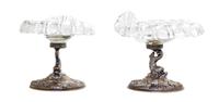 A Pair of German Silver and Glass Compotes, First Half 20th Century, having etched glass shell form bowls raised on dolphin form suppor