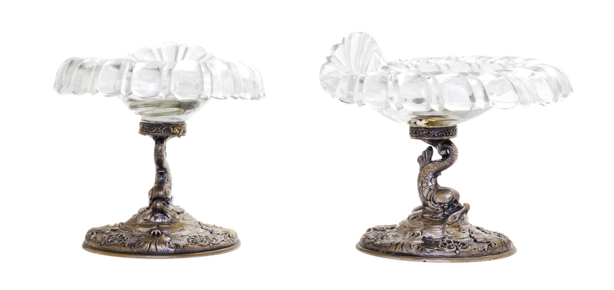 A Pair of German Silver and Glass Compotes, First Half 20th Century, having etched glass shell form bowls raised on dolphin form suppor