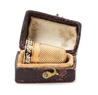 An American Yellow Gold and Enamel Thimble, , the knurled top and body above an engine turned band with an engraved cartouche and a flo