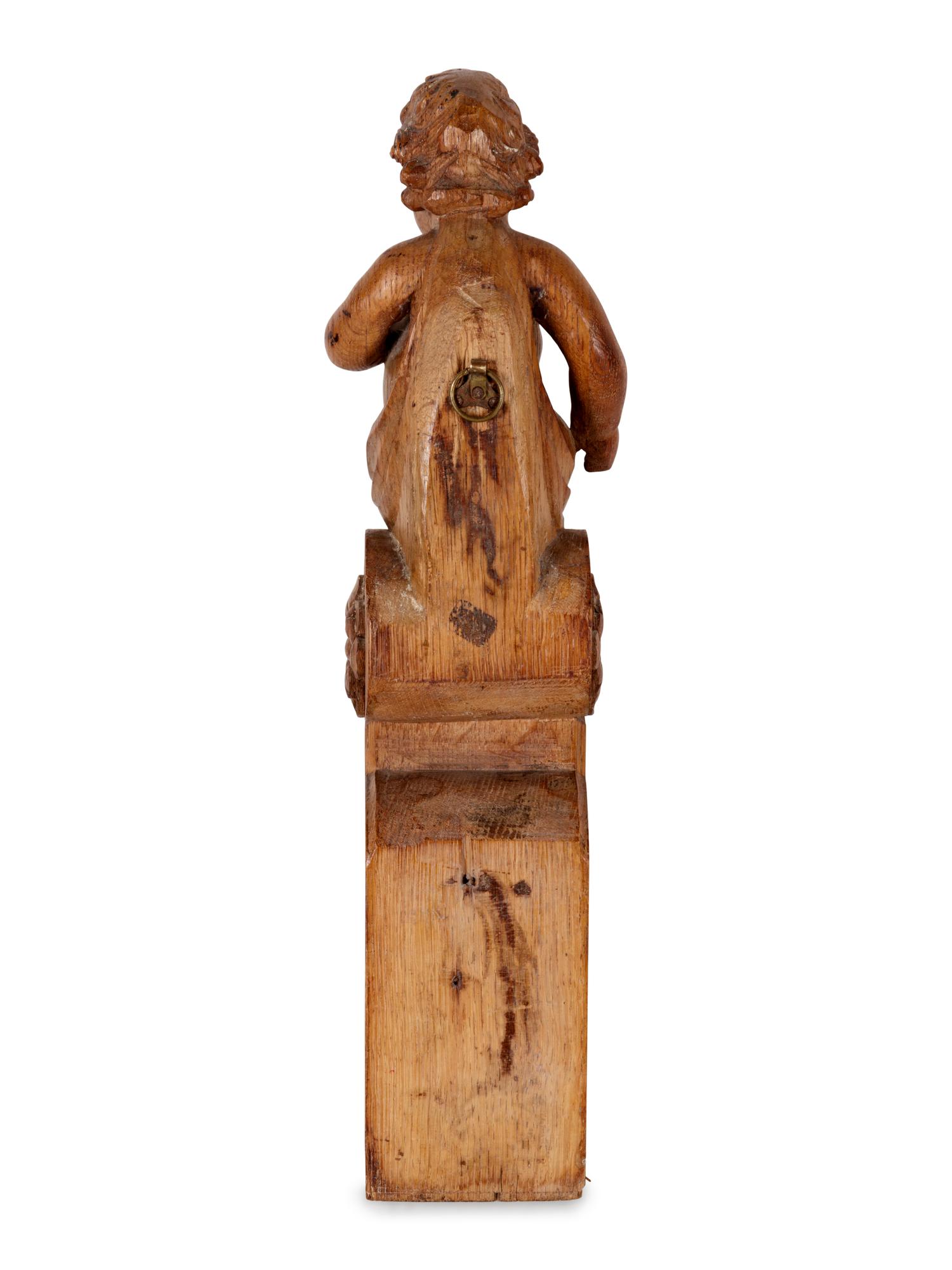 A Continental Carved Oak Figural Bracket in the Form of a Putto