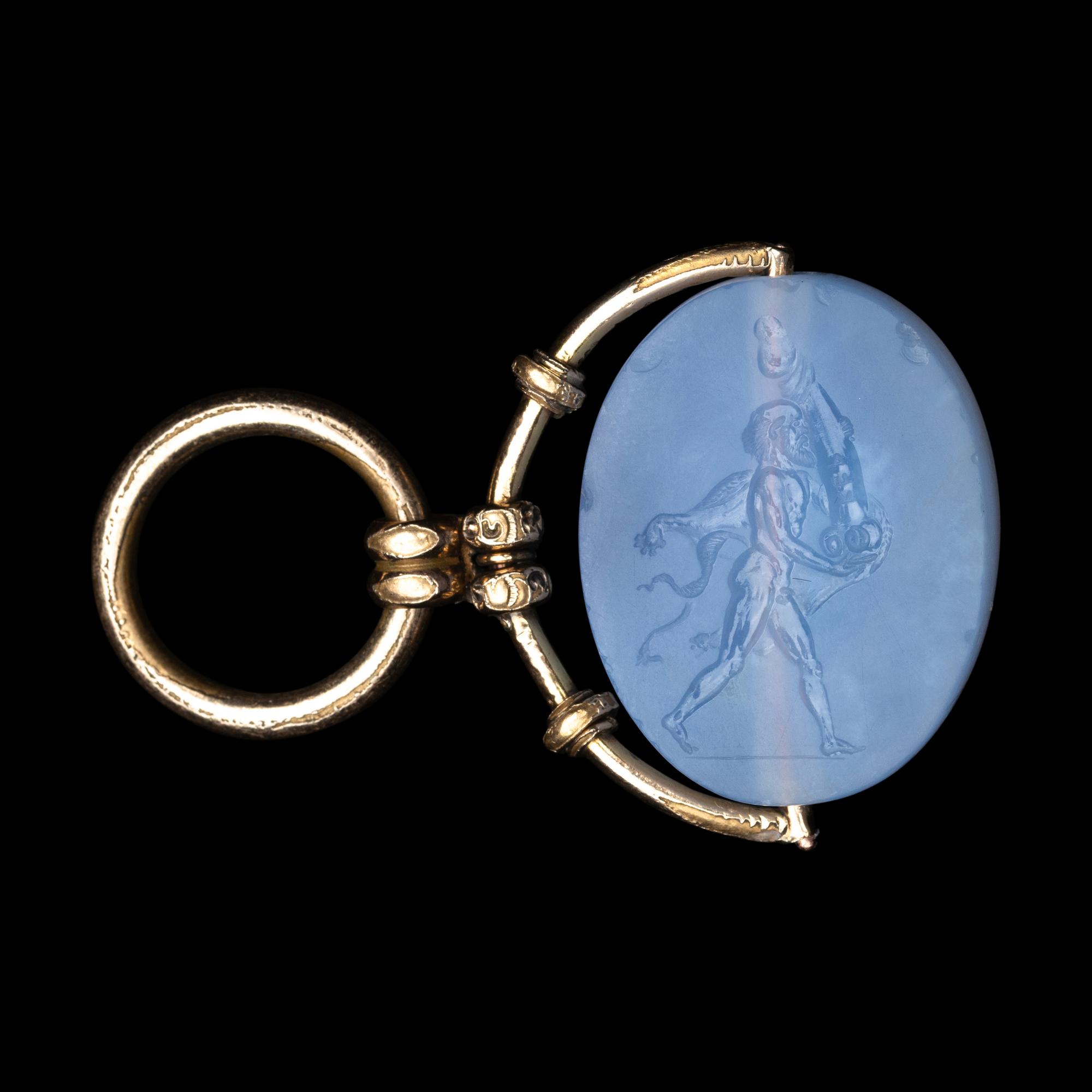 A Greek Blue Chalcedony Intaglio with a Satyr Holding a Herm — Set in a gold pendant