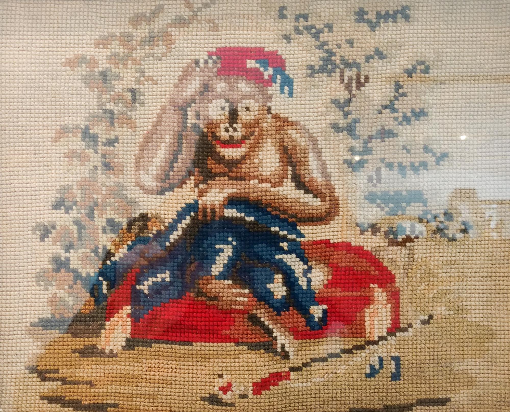 A Framed Needlepoint of a Monkey Height 9 x width 11 1/4 inches.