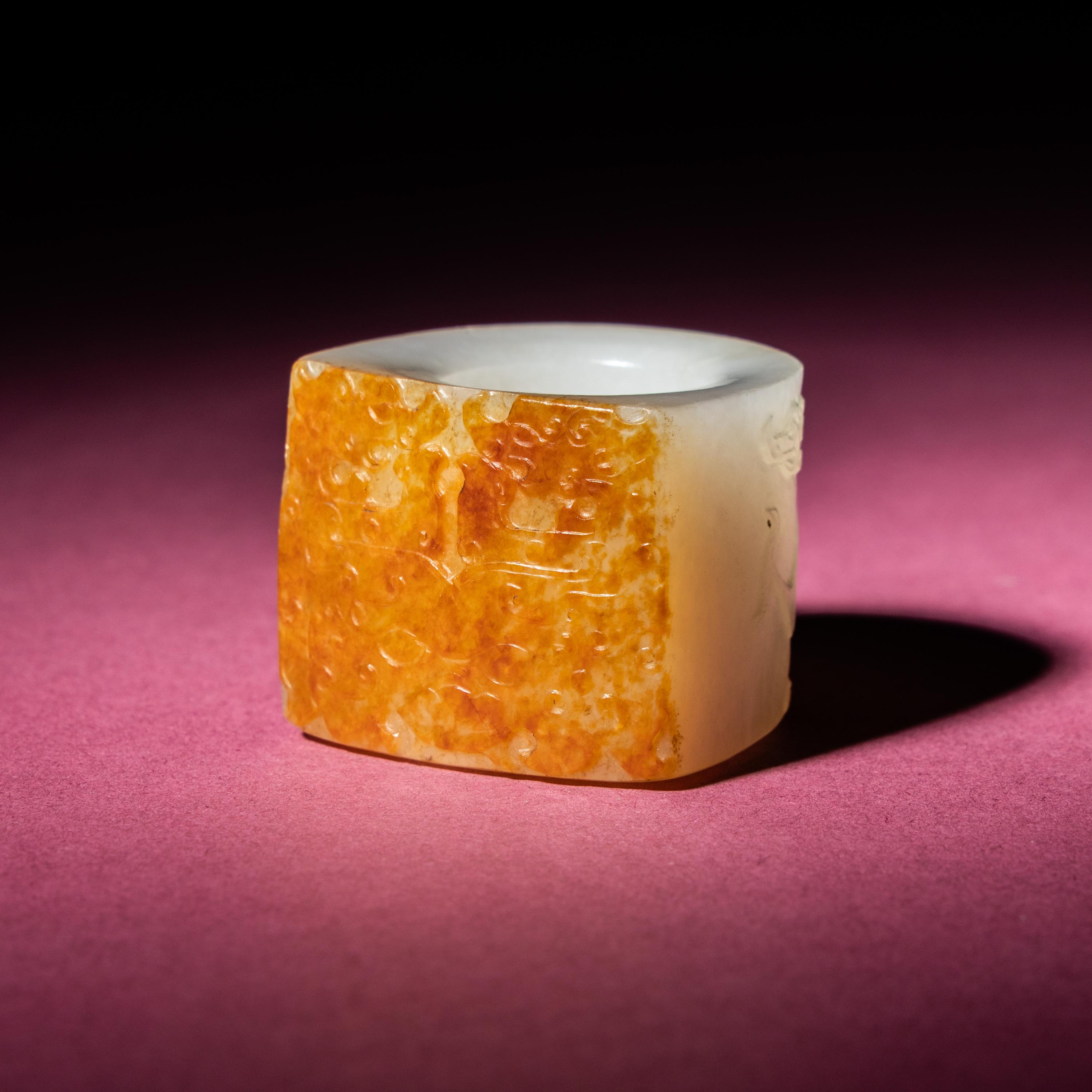 A Chinese Russet and White Jade 'Taotie and Chilong' Archer's Ring, 18th Century — 清中期 白玉留皮饕餮螭龍紋扳指