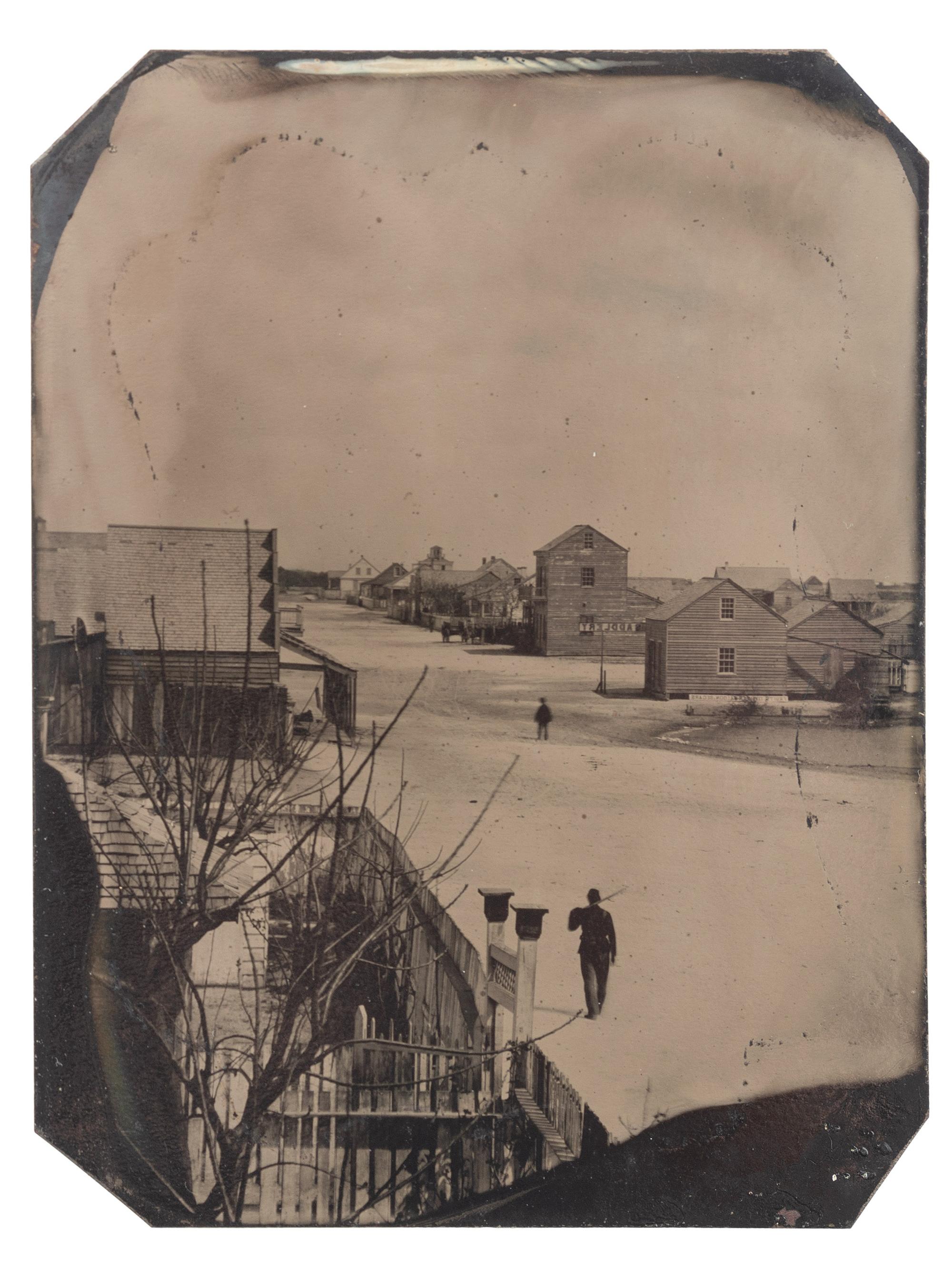 [CIVIL WAR]. Quarter plate tintype of a soldier walking down the street of a likely Carolina town, with sign for oyster saloon partly visible.