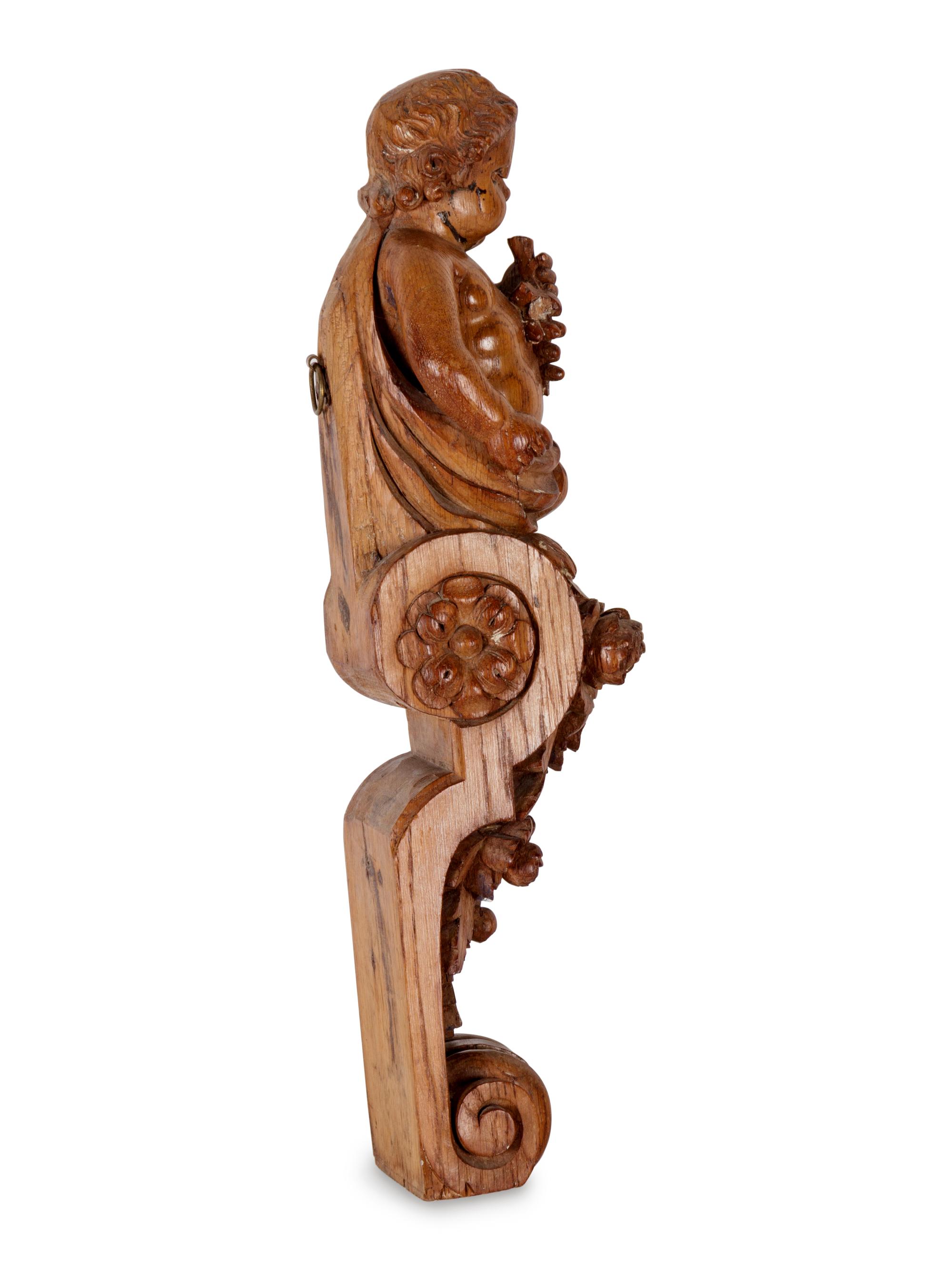 A Continental Carved Oak Figural Bracket in the Form of a Putto