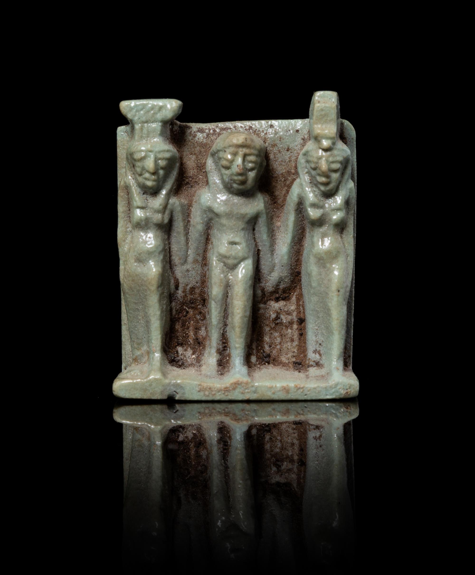 An Egyptian Faience Triad Amulet Height 1 5/8 x width 1 1/4 inches. — LATE PERIOD, DYNASTY 26, 664-525 B.C.E.