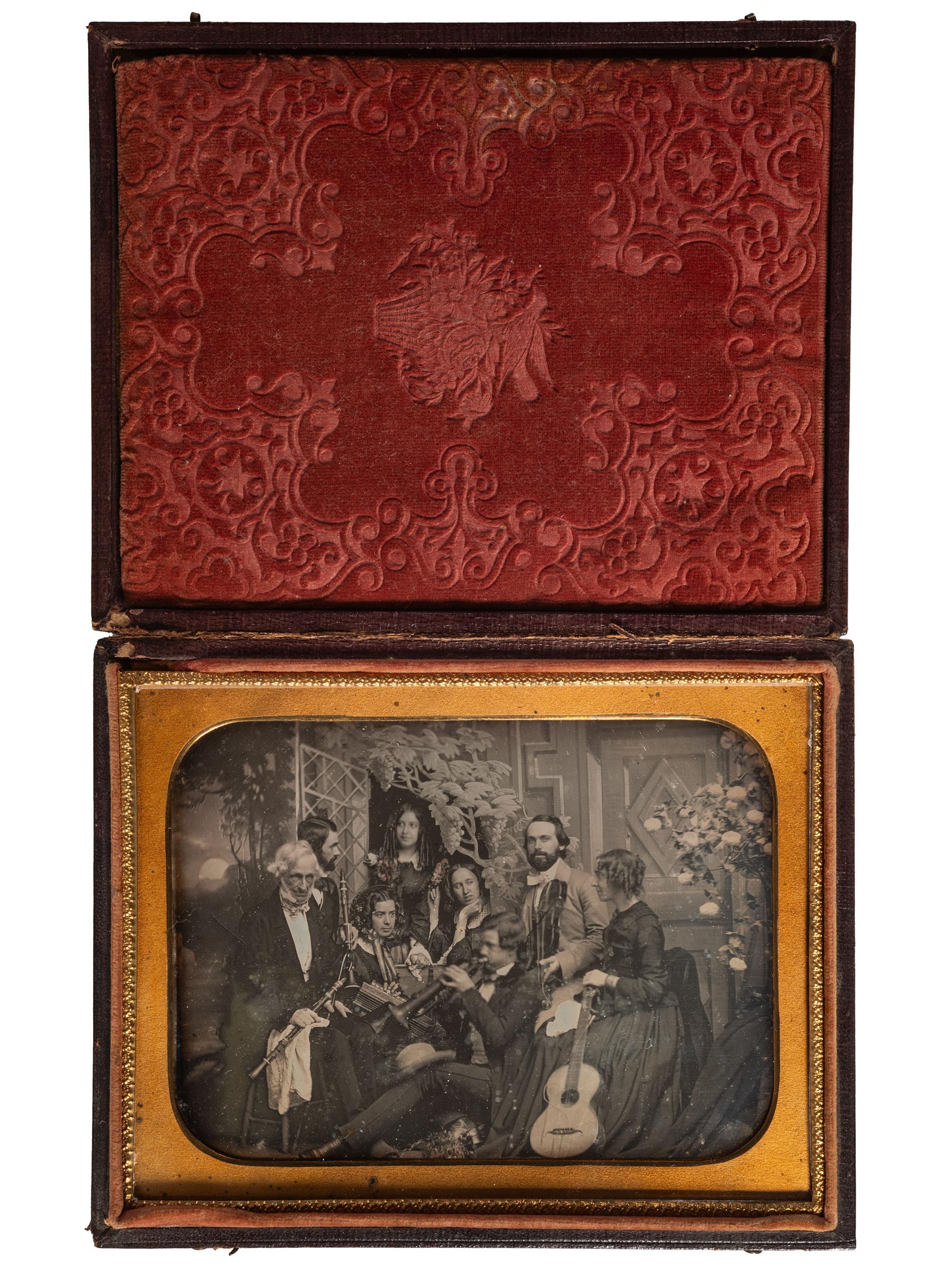 [EARLY PHOTOGRAPHY]. Half plate daguerreotype scene of a group of playful musicians and guests posed together with diverse instruments before a detailed studio backdrop.