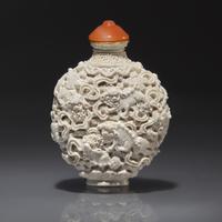 A Chinese Molded White-Glazed Porcelain "Buddhist Lions" Snuff Bottle, Qing Dynasty, Jiaqing Mark and of the Period — 清嘉慶 白釉模印鏤雕獅戲繡球圖鼻煙壺