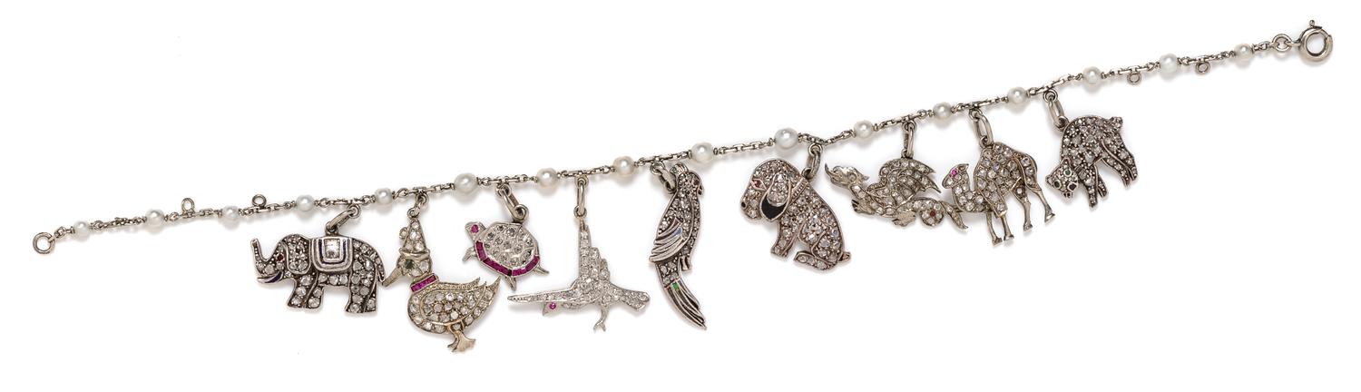 An Art Deco White Gold, Cultured Pearl, Diamond, Ruby and Polychrome Enamel Charm Bracelet with 9 Attached Charms, 9.50 dwts.