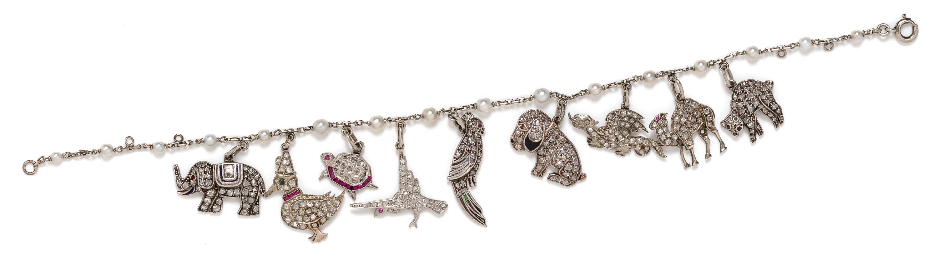An Art Deco White Gold, Cultured Pearl, Diamond, Ruby and Polychrome Enamel Charm Bracelet with 9 Attached Charms, 9.50 dwts.