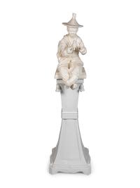 A Continental Blanc de Chine Figure of a Seated Chinese Man on a Pedestal