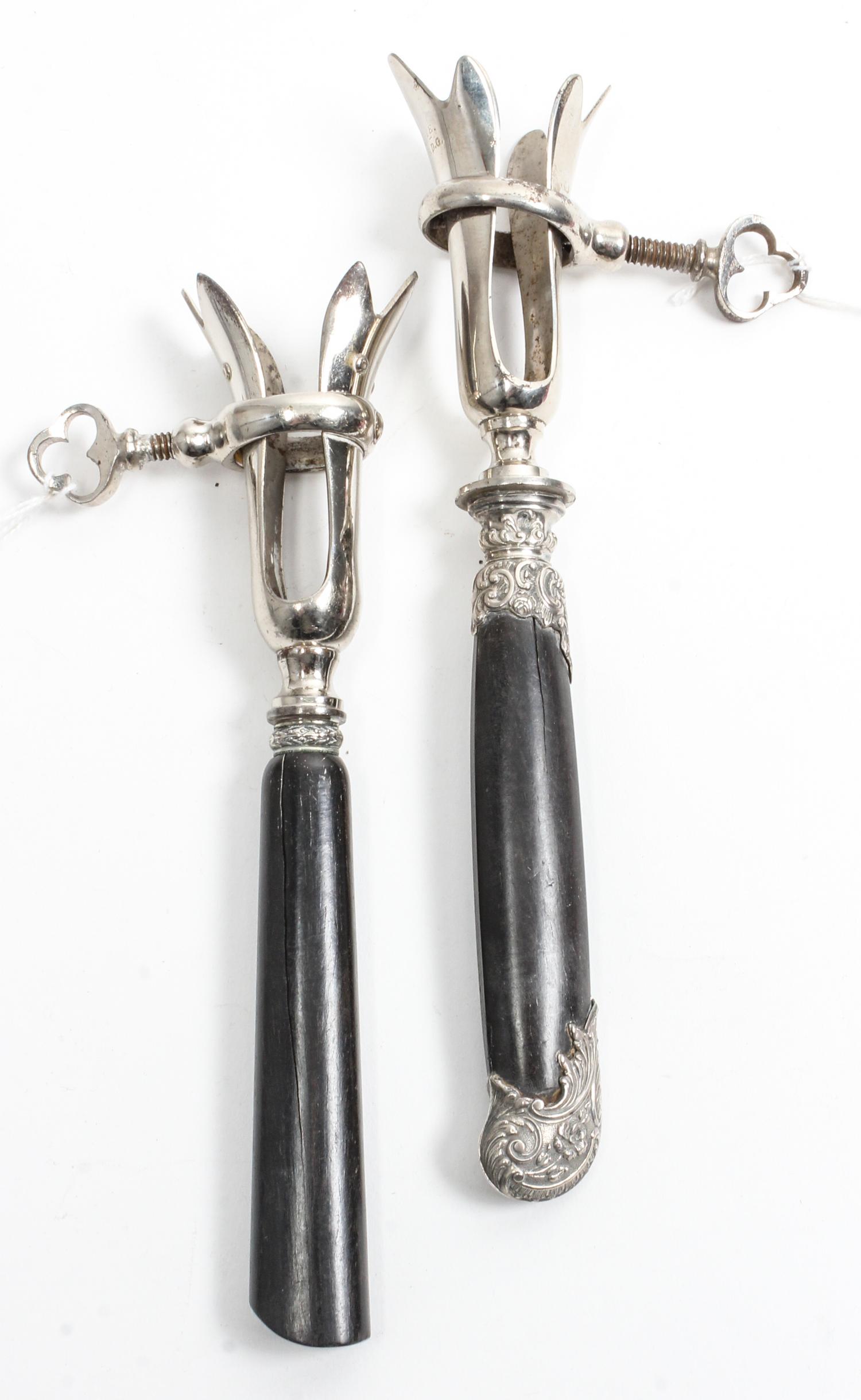 Two French Silver Mounted Bone Holders, makers' marks obscured, each having an ebony handle and a silvered metal clamp.