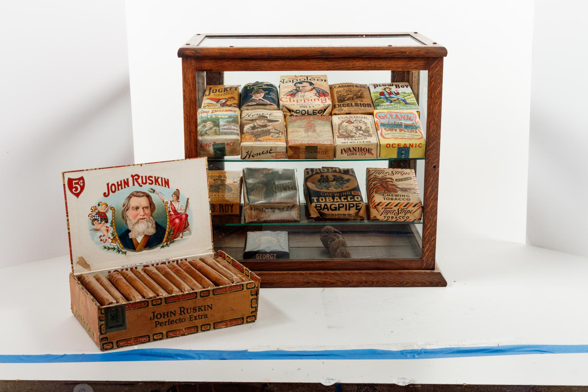 A Collection of Fifteen Tobacco Cartons and a Tobacco Rope in Display Case