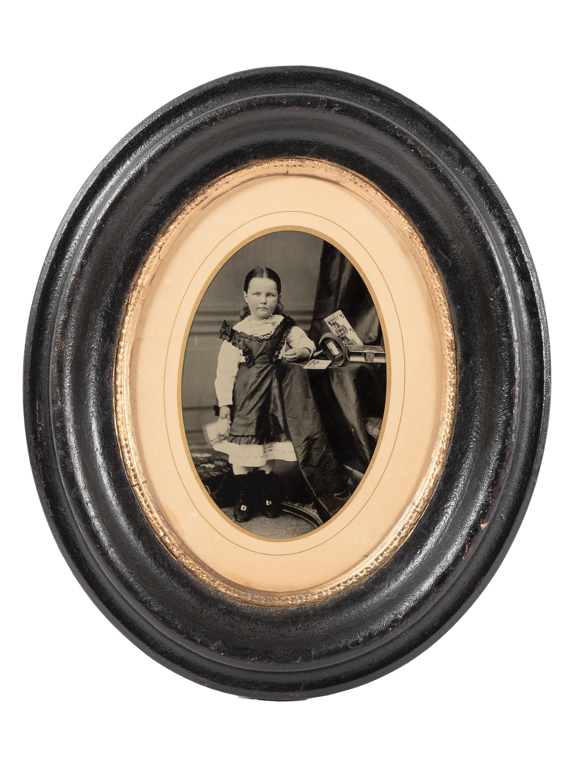 [EARLY PHOTOGRAPHY]. Tintype portrait of a little girl posed with stereoviews, viewer, and photo album.