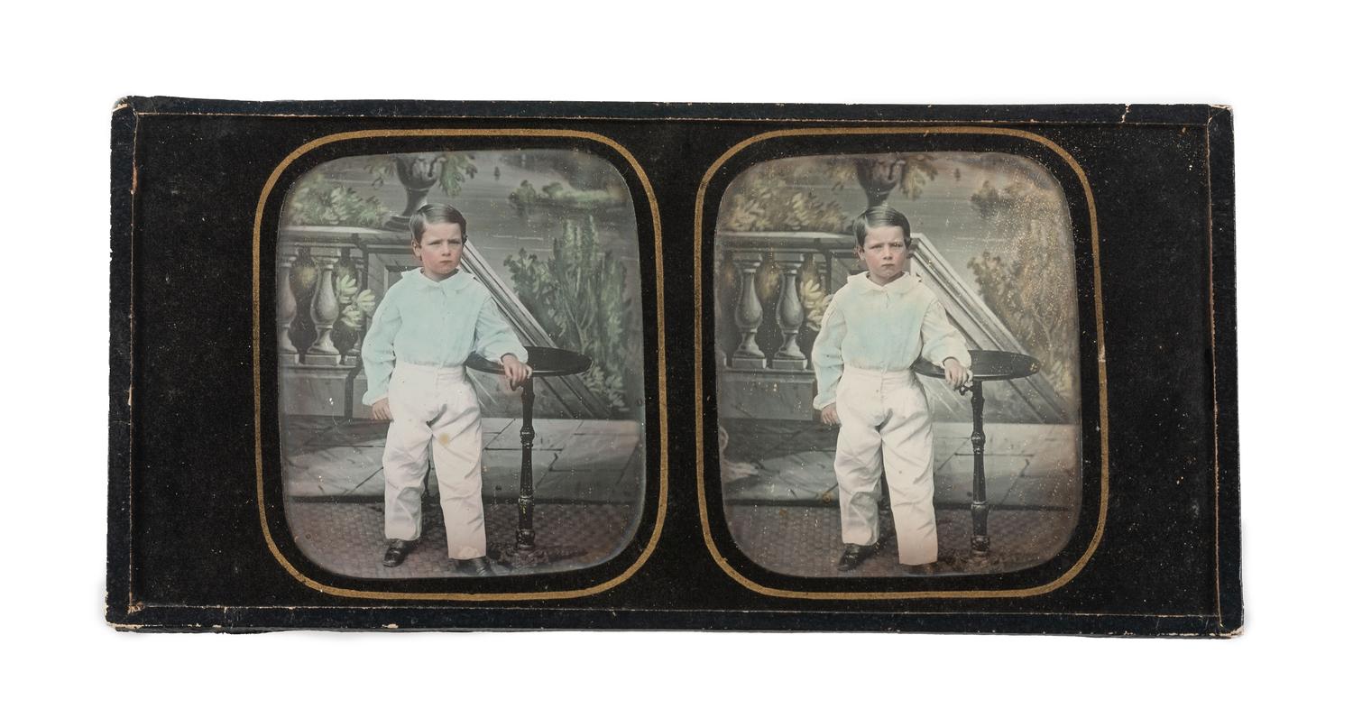 [EARLY PHOTOGRAPHY]. Hand-tinted stereodaguerreotype featuring a young boy standing next to a candlestand.