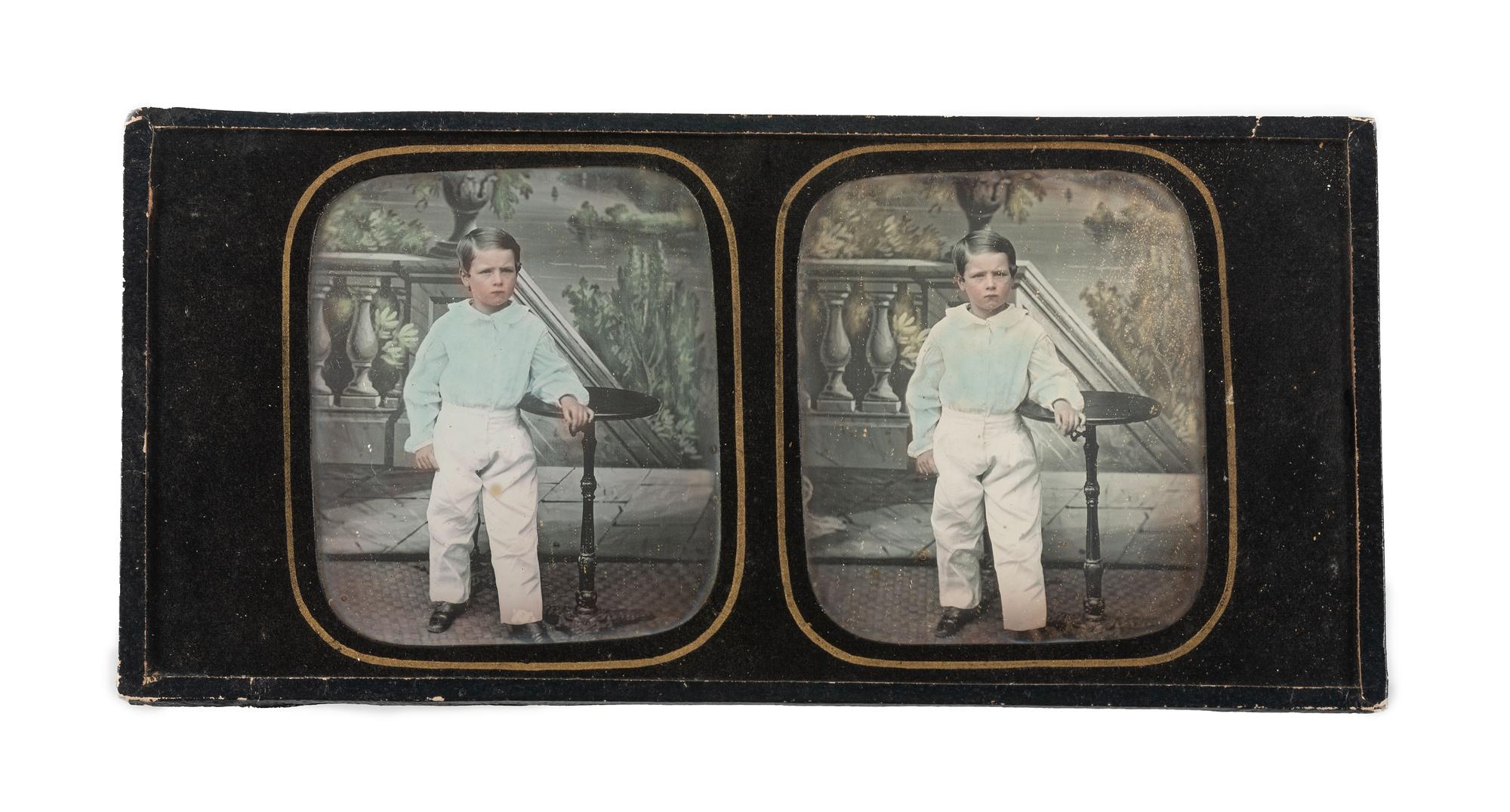[EARLY PHOTOGRAPHY]. Hand-tinted stereodaguerreotype featuring a young boy standing next to a candlestand.
