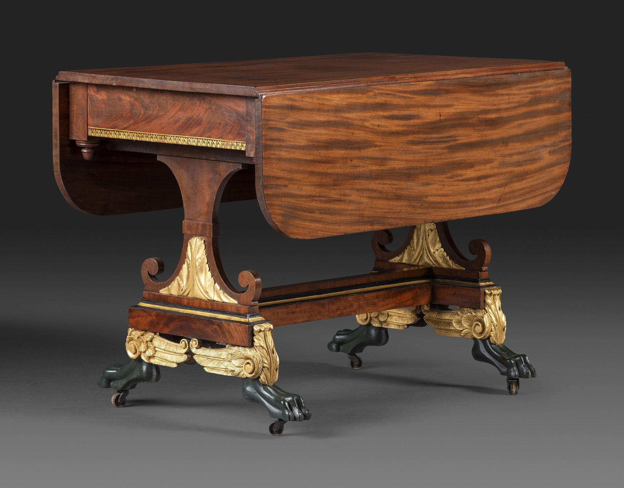 A Classical Parcel Gilt and Ebonized, Figured Mahogany Paw-Foot Drop-Leaf Table