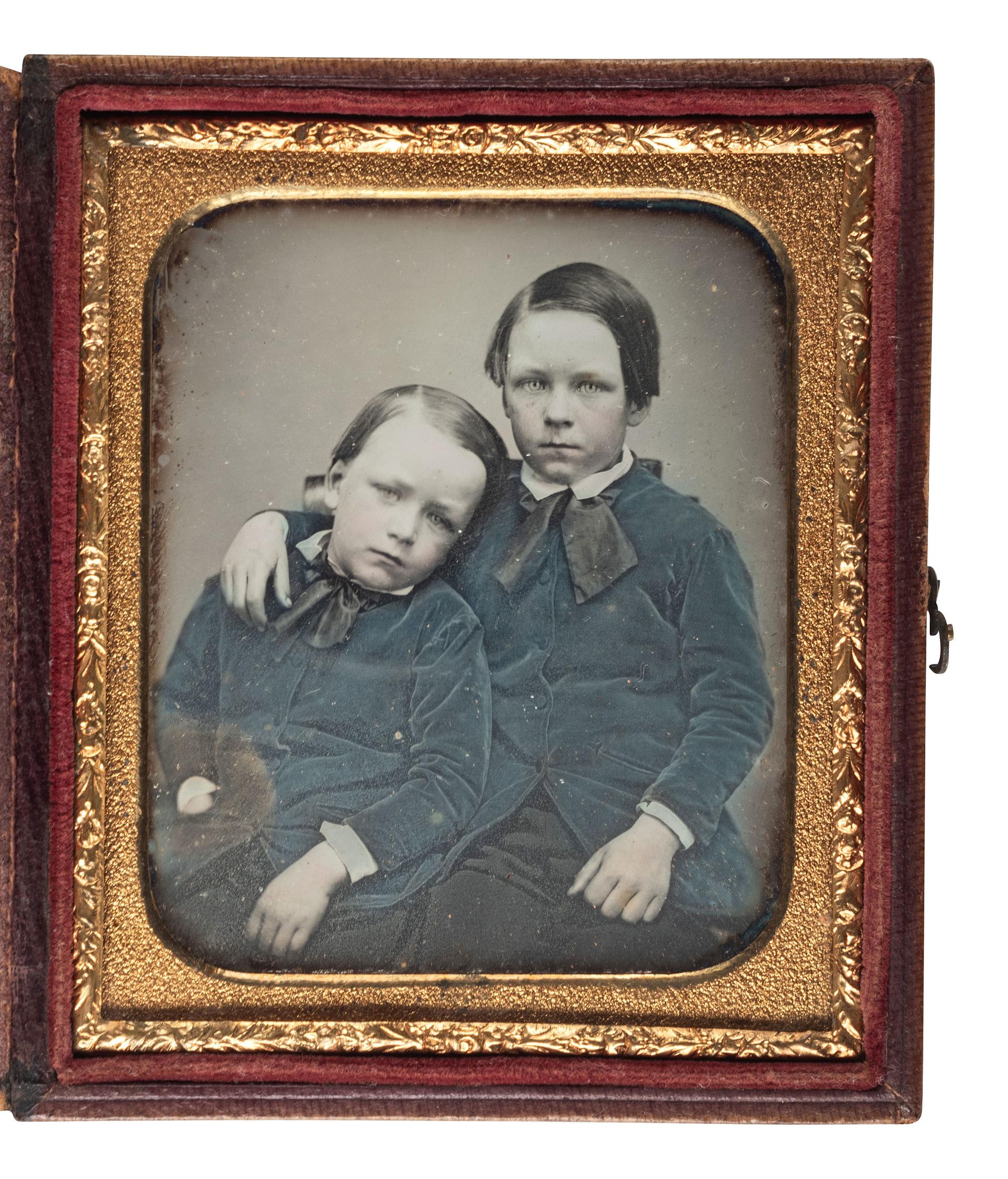 [EARLY PHOTOGRAPHY]. Sixth plate daguerreotype portrait of a pair of young brothers wearing blue jackets and embracing in a loving pose.