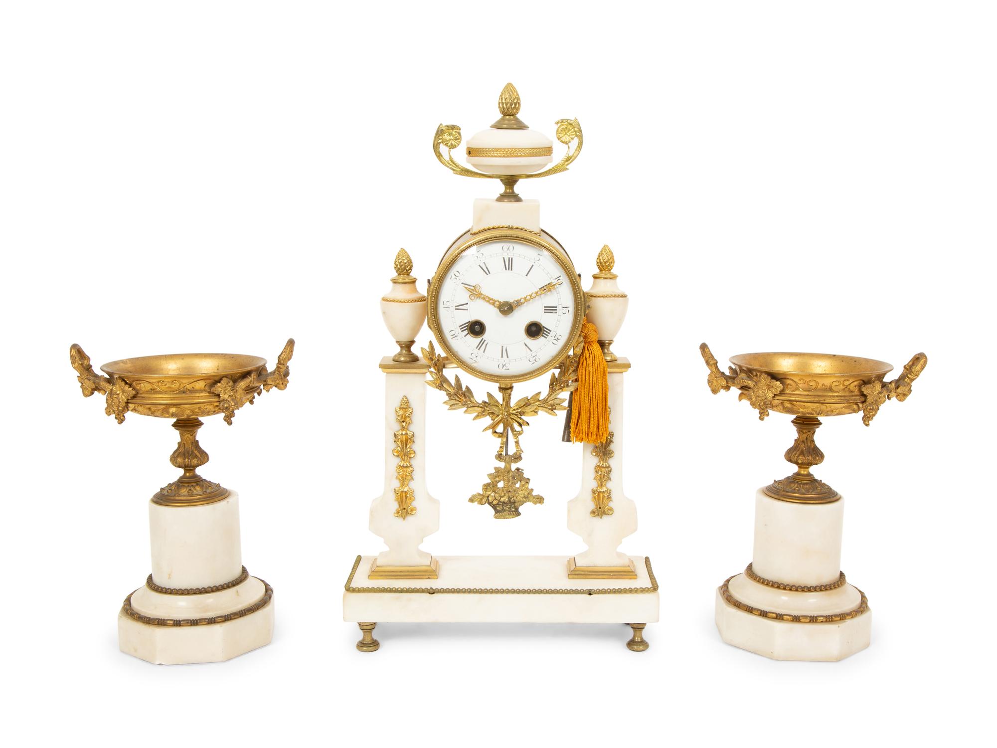 A French Gilt Bronze and Marble Mantel Clock with an Associated Pair of Urns