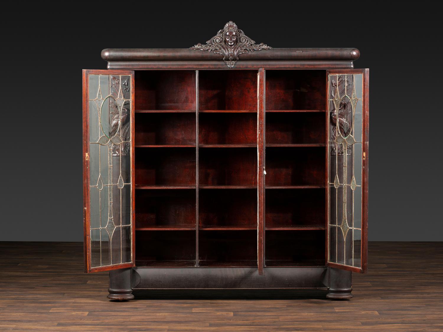 An Aesthetic Movement Crane and Mask Carved Mahogany and Glass Paneled Bookcase