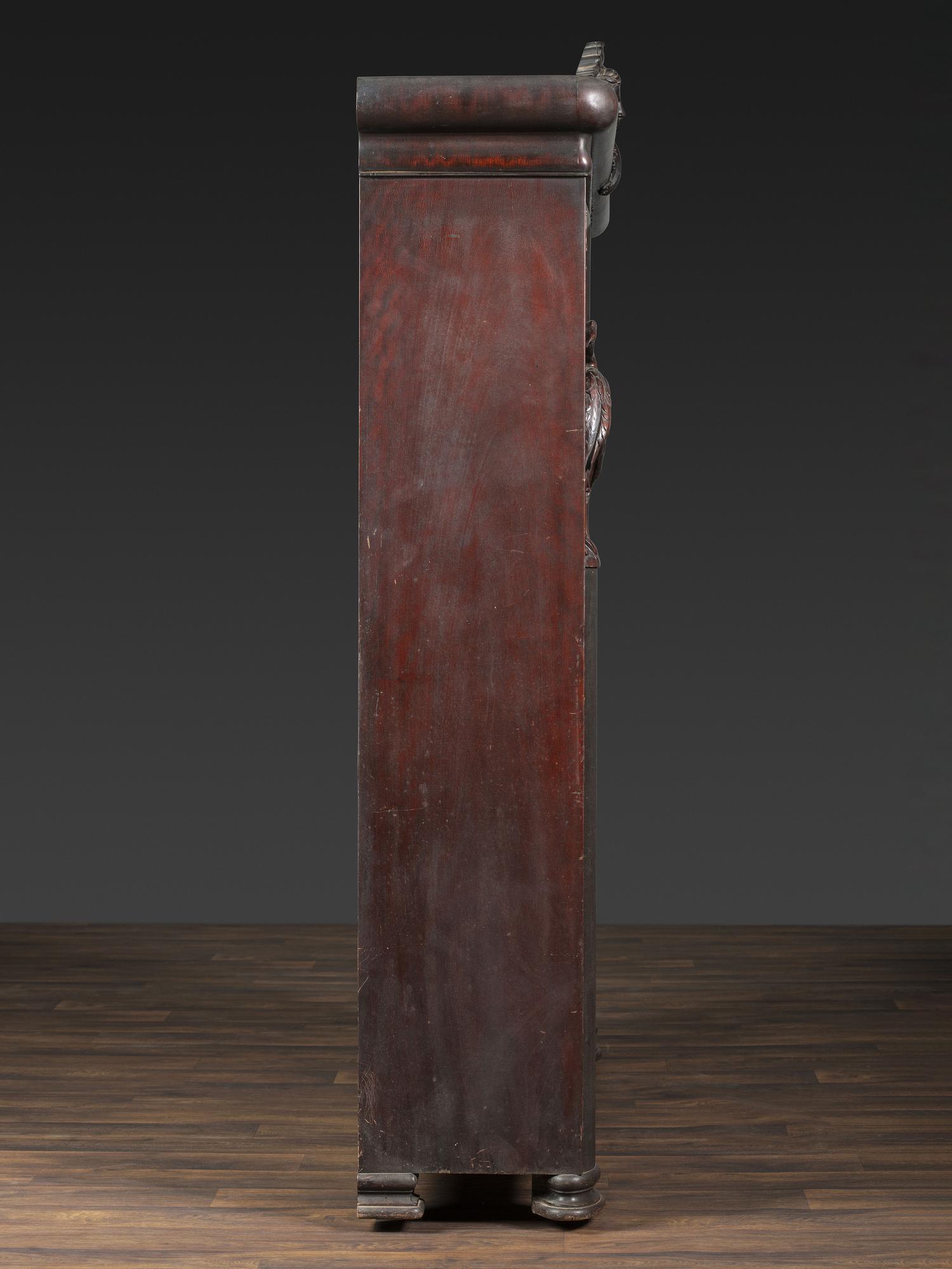 An Aesthetic Movement Crane and Mask Carved Mahogany and Glass Paneled Bookcase