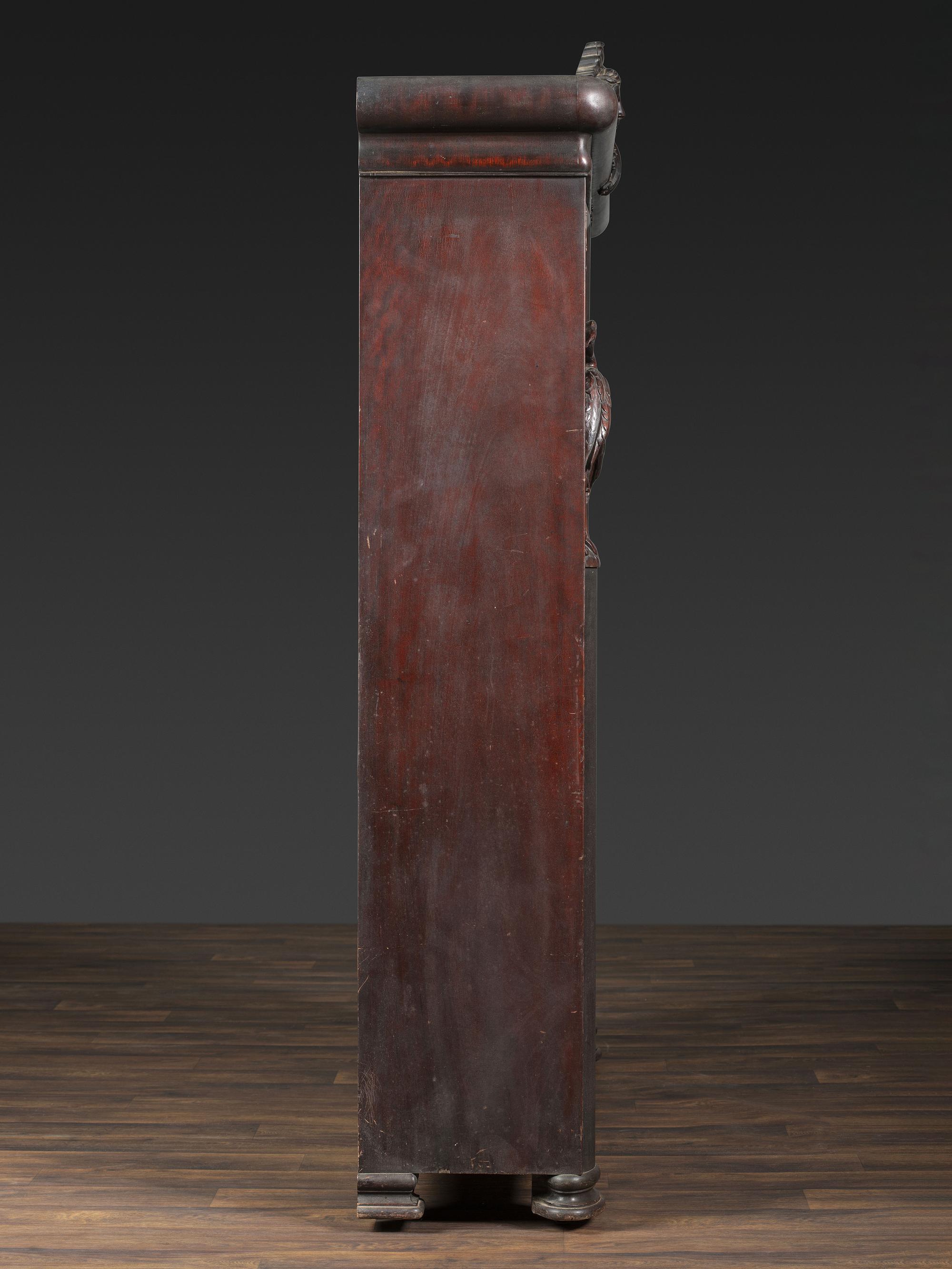 An Aesthetic Movement Crane and Mask Carved Mahogany and Glass Paneled Bookcase
