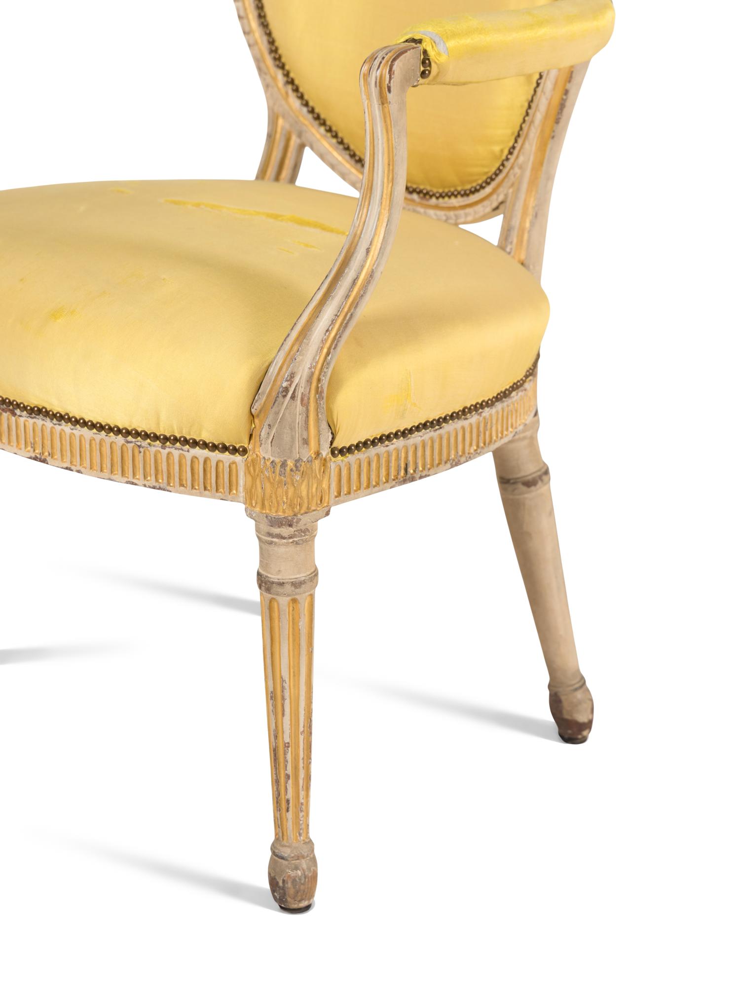 A Pair of George III Carved, Grey-Painted and Parcel Gilt Armchairs