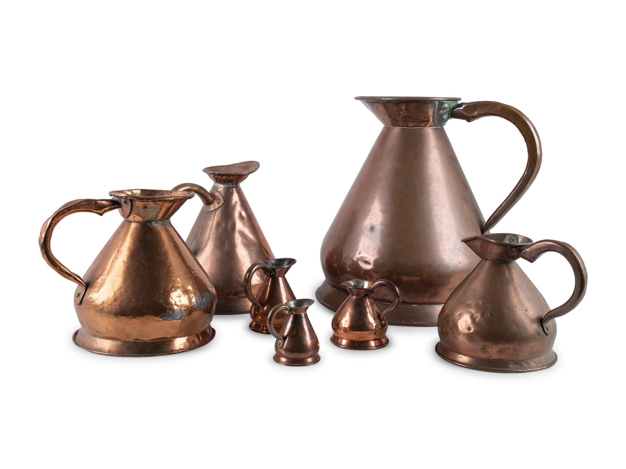 Seven Copper Graduated Pitchers