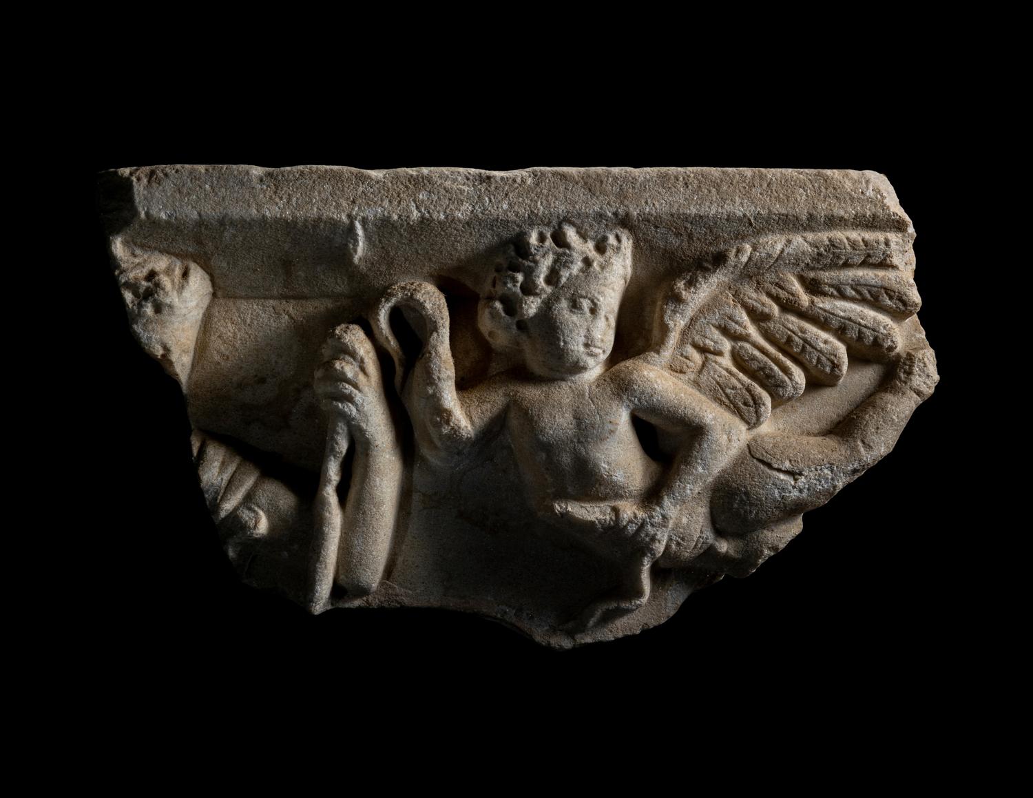 A Roman Marble Sarcophagus Fragment with Eros Holding Snakes